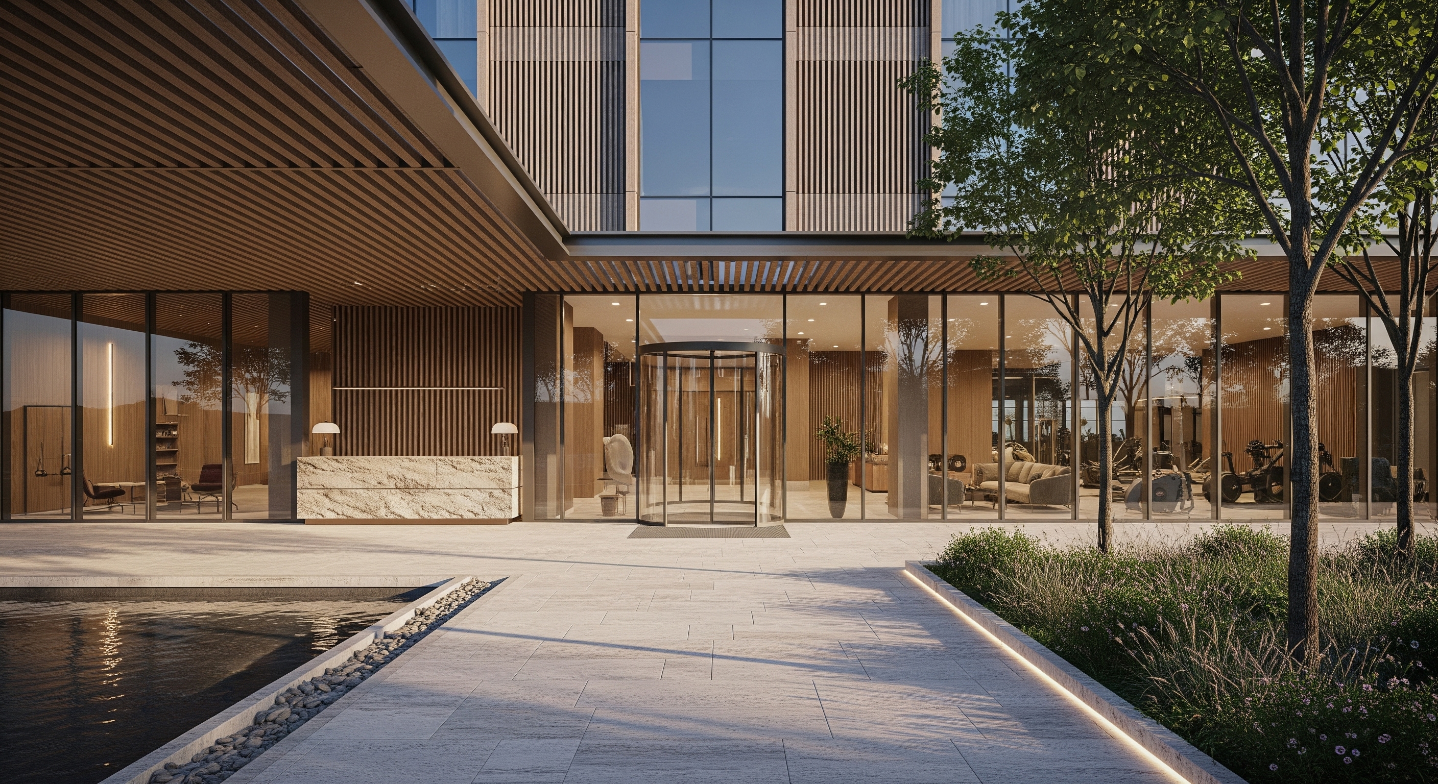 Entrance of an office building with a timber-slat facade, a water feature, stone paving and young trees